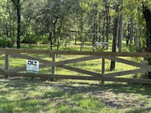 A long, newly constructed wooden farm fence alongside a road, completed by DLT Land Management in Tampa, FL.