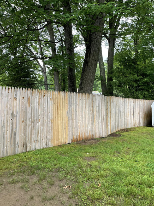 A long wooden picket fence after repair and maintenance by Digby Handyman Services LLC in Cranston, RI.