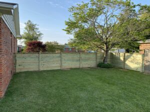 A newly constructed long wooden pier or dock extending into the water, built by Dutch Deck and Fence in Norfolk, VA.