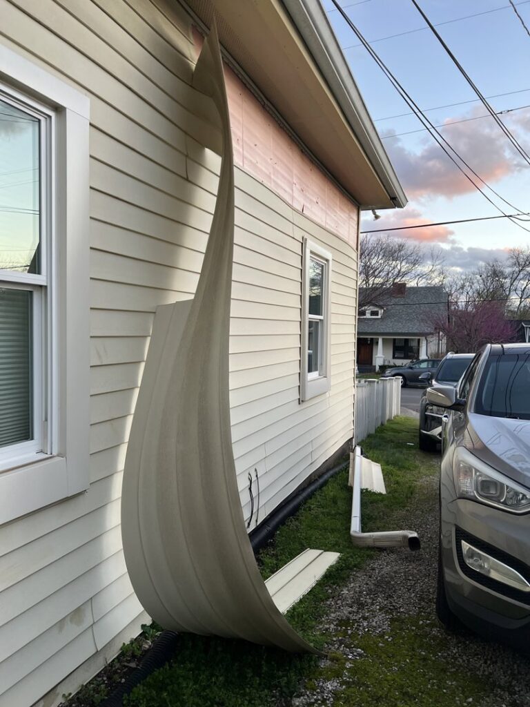 Damaged siding peeling off a house, showing the need for repair by Music City Exteriors in Nashville, TN