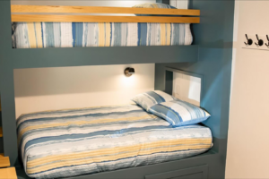 A close-up of the lower custom bunk bed featuring a wall-mounted light fixture and a built-in cubby by An Extra Hand in Indianapolis, IN.