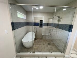 A luxurious bathroom remodel with a freestanding tub and a large glass shower by MC Master Construction in League City, TX