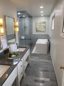 A luxurious bathroom renovation featuring a double vanity, large shower, and freestanding tub by Infinite Creations Construction, LLC in Denver, CO