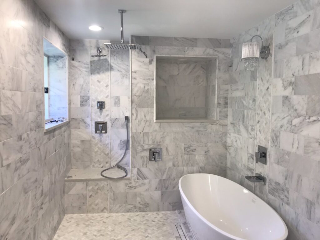 A luxurious bathroom with marble tiling, a spacious walk-in shower, and a modern freestanding tub by Technically Aesthetic General Contractors in Johnson City, TN.