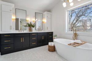 A luxurious master bathroom renovation featuring a double black vanity, freestanding tub, and large window by Westrick Homes in St. Louis, MO.