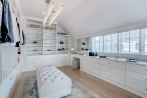 A luxurious walk-in closet with extensive shelving, drawers, and a built-in vanity by Closet Creations Inc. in Sleepy Hollow, NY.