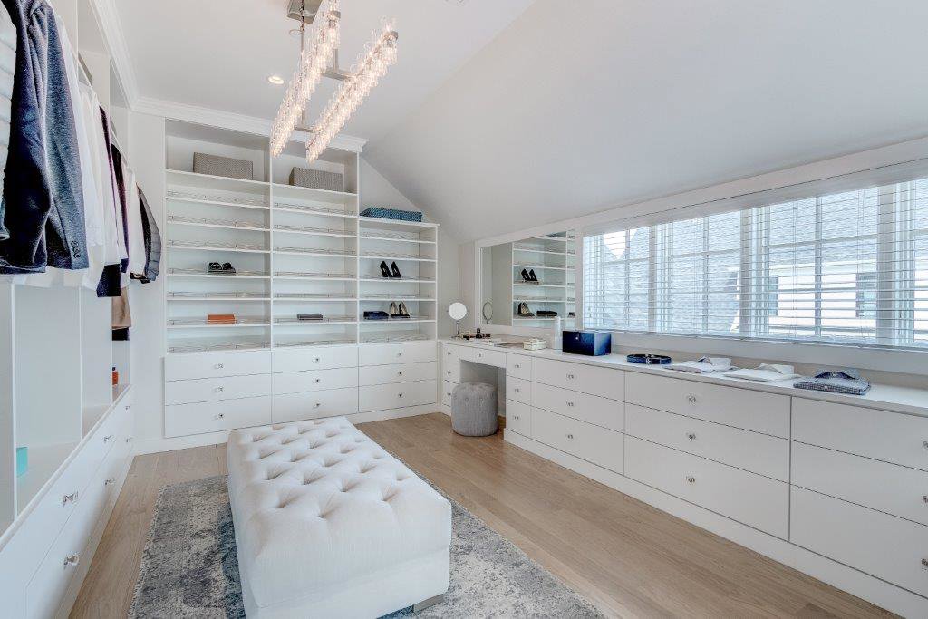 A luxurious walk-in closet with extensive shelving, drawers, and a built-in vanity by Closet Creations Inc. in Sleepy Hollow, NY.