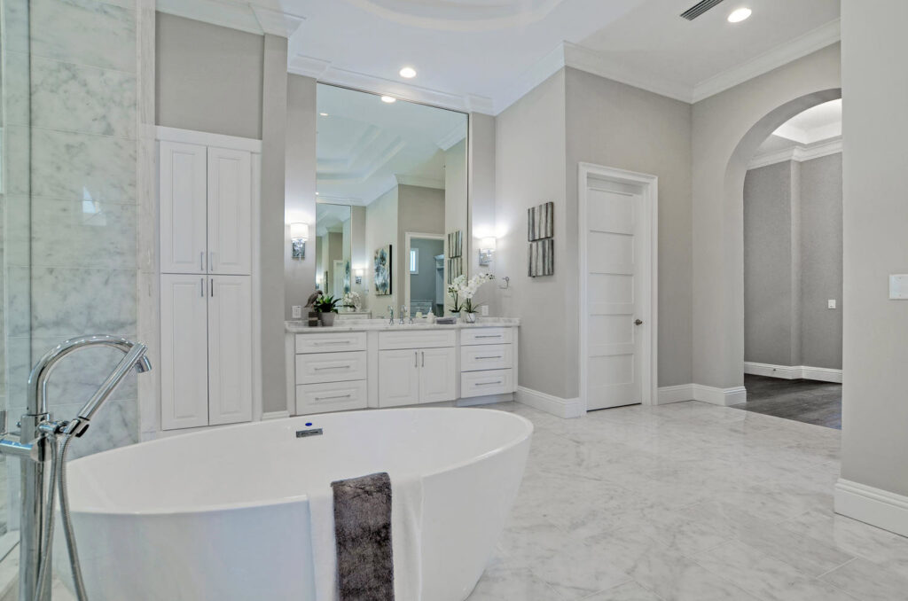 A luxurious bathroom with a freestanding soaking tub, large vanity, and marble floors, a project by TamLin Homes Inc in Tampa, FL