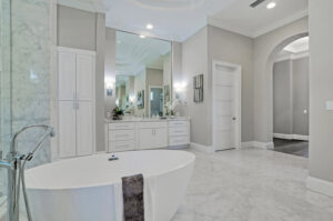A luxurious bathroom with a freestanding soaking tub, large vanity, and marble floors, a project by TamLin Homes Inc in Tampa, FL