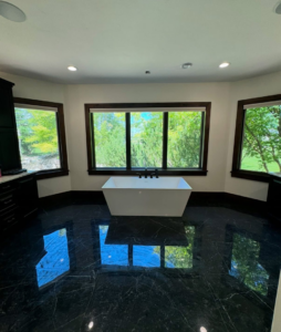 A luxurious bathroom featuring black marble floor tiles and a modern freestanding tub installed by Patriot Tile LLC in Skiatook, OK.