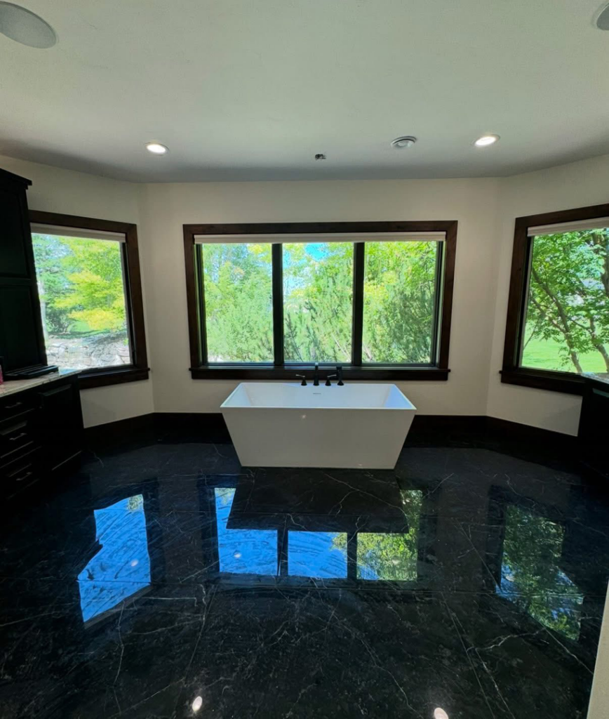A luxurious bathroom featuring black marble floor tiles and a modern freestanding tub installed by Patriot Tile LLC in Skiatook, OK.