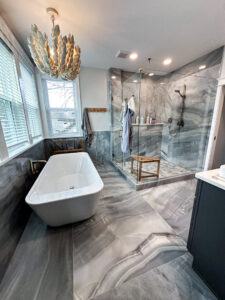 A luxurious bathroom remodel featuring a freestanding tub, glass shower, and elegant grey marble-look tiles by Kore Construction LLC in Cincinnati, OH.