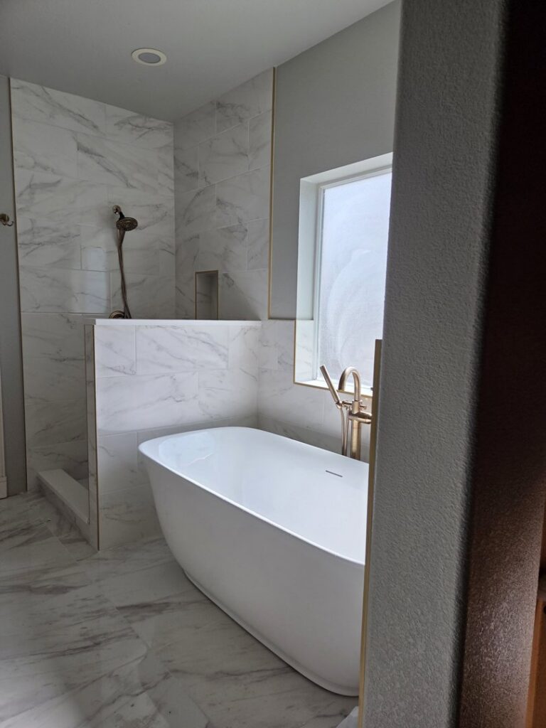 Luxury bathroom remodel with marble-look tile shower and freestanding tub by APJ Construction Inc. in El Paso, TX.