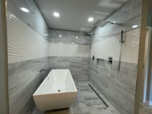 A luxury bathroom remodel featuring large grey tiles, a freestanding tub, and a spacious shower by Prestige Services in Annapolis, MD.