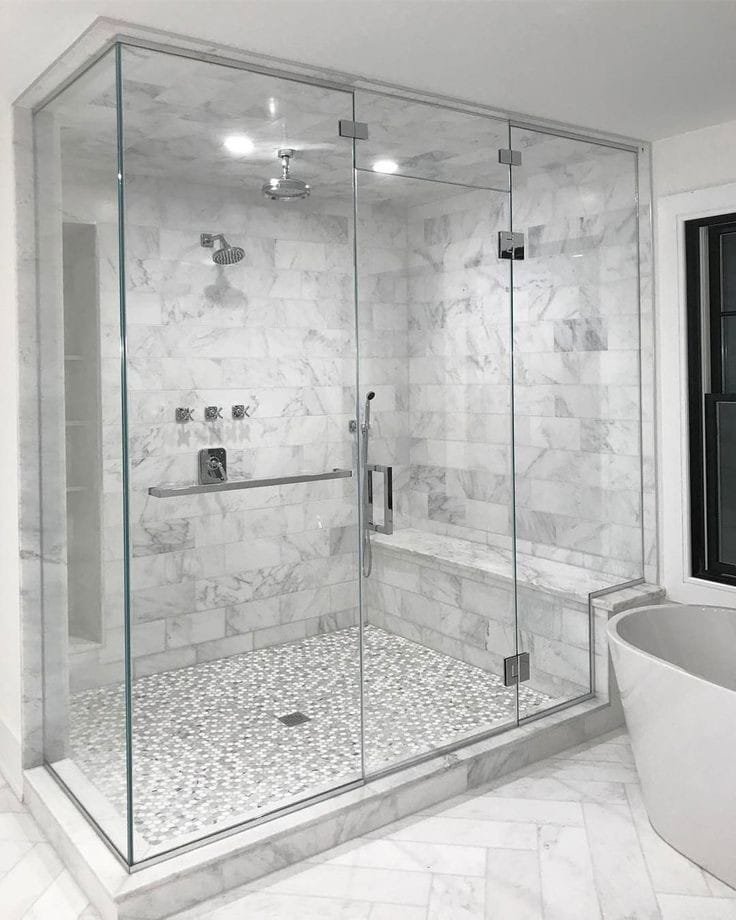 A luxurious bathroom renovation featuring a spacious glass shower enclosure and marble-look tiles by Rapid Restoration and Construction in Mesa, AZ.