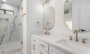 A luxurious bathroom renovation featuring dual vanity, gold fixtures, and a walk-in shower by Home Platinum Services, LLC in Plano, TX