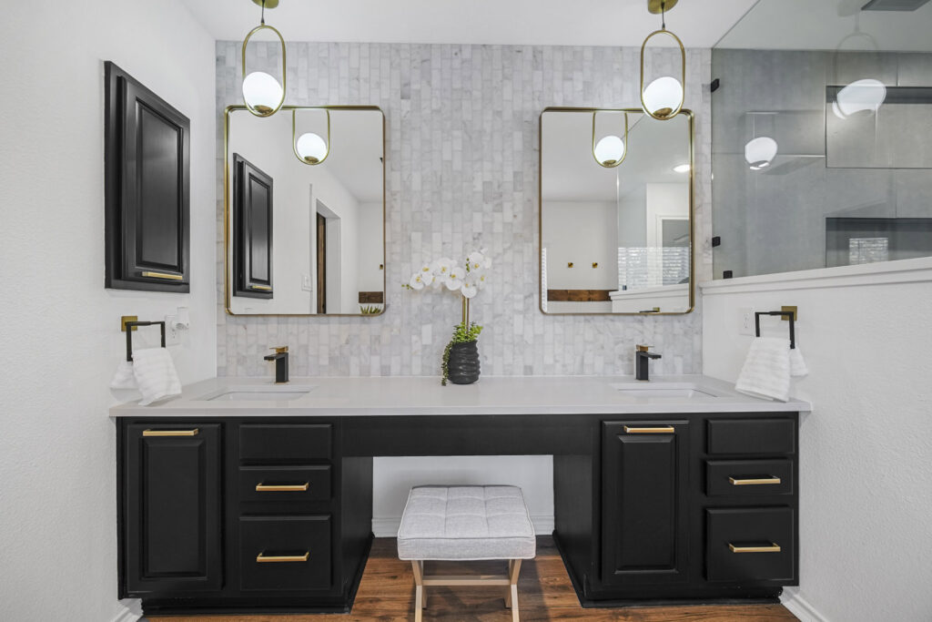 A luxurious bathroom featuring a double vanity with marble-look tile and modern lighting by HomeNovate in San Antonio, TX.