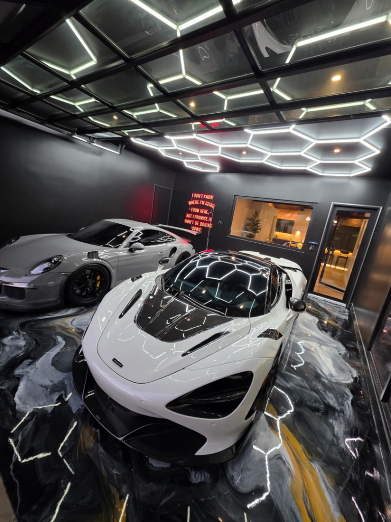 A luxury garage featuring a custom epoxy floor coating and hexagonal lighting by Orange Door Custom Coatings in Phoenix, AZ.