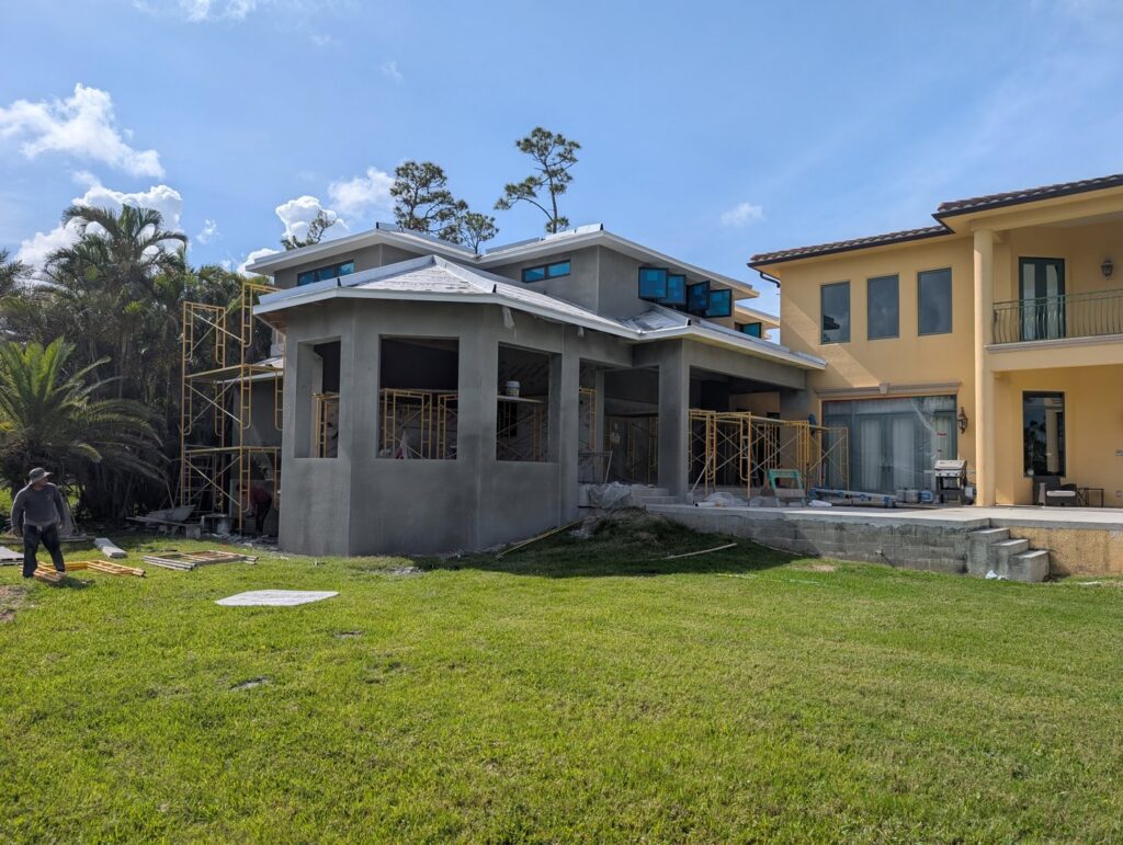 A luxury home under construction with scaffolding and stucco work in progress by Rock's Custom Homes in St. Petersburg, FL.