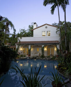 A luxury home exterior with a swimming pool and lush landscaping at dusk by Madison Construction Group, Inc. in Miami, FL
