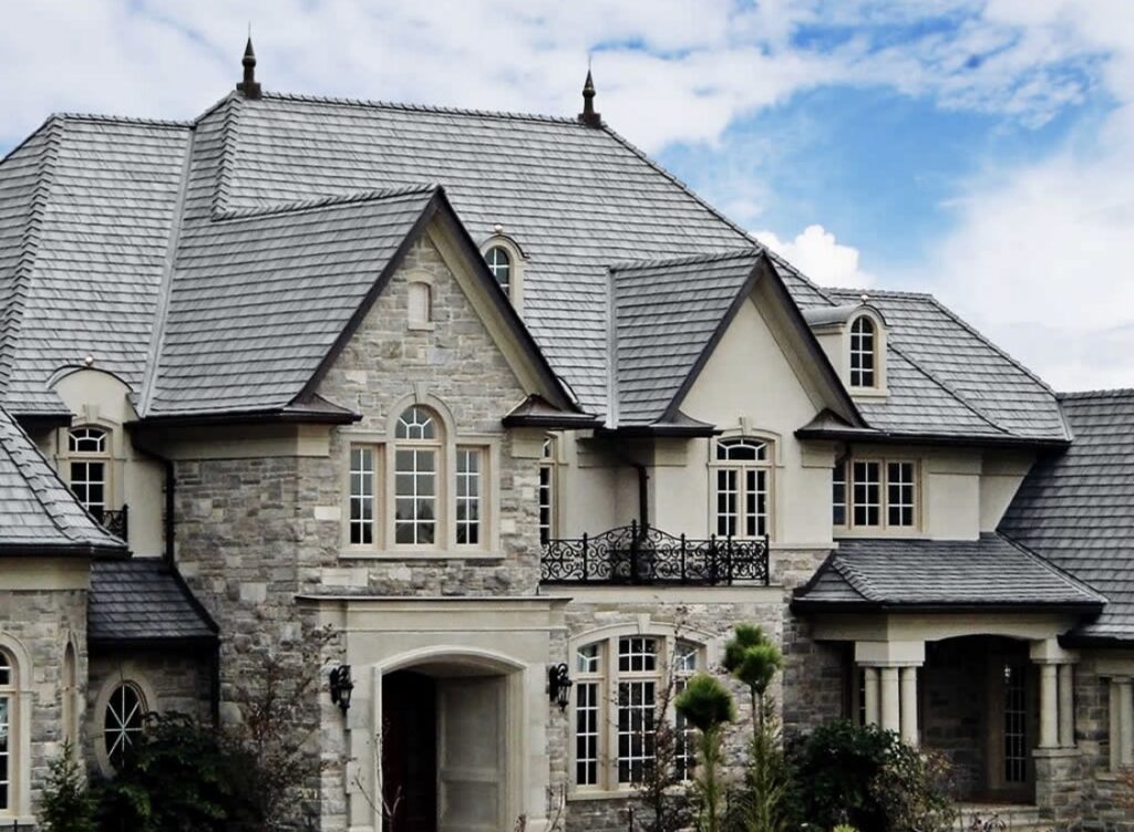 A beautiful luxury home with a stone facade and intricate grey shingle roof, showcasing work by First Contracting Group in Rockford, IL.