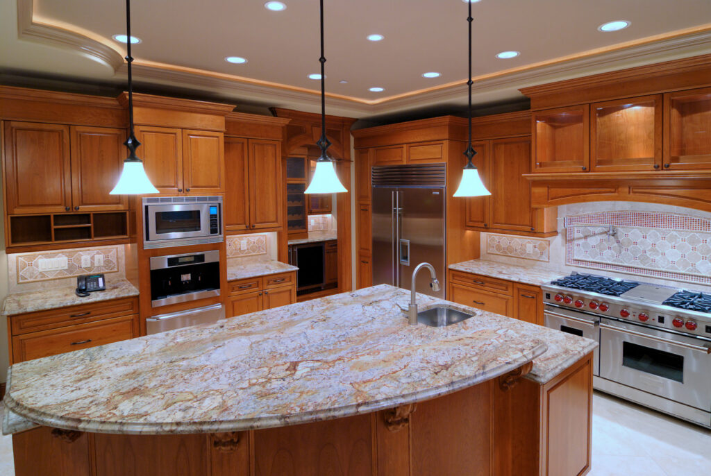 A luxurious kitchen featuring light wood cabinets, granite countertops, a large island, and high-end appliances by Creative Building & Remodeling in Warren, MI
