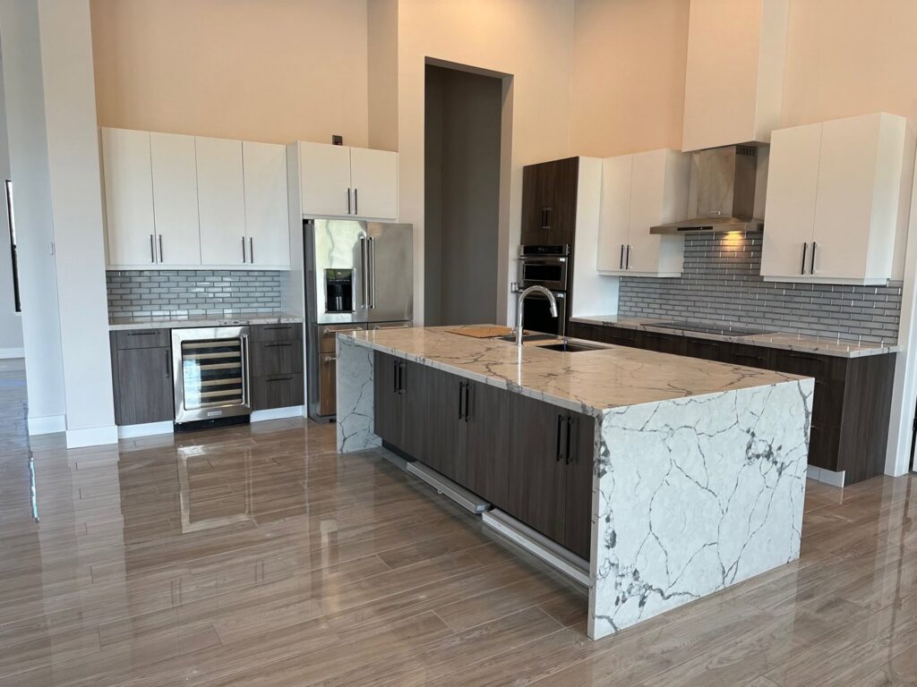 A luxury kitchen remodel with white and dark wood cabinets, a large island, and stainless steel appliances by LJ Builders in Chandler, AZ
