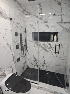 A luxury bathroom shower remodel featuring marble-look tiles and a modern black shower system by Luis handyman service in Albuquerque, NM