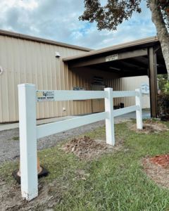 The LV Fence and Gates business logo displayed on a newly installed white vinyl fence post in Jacksonville, FL.