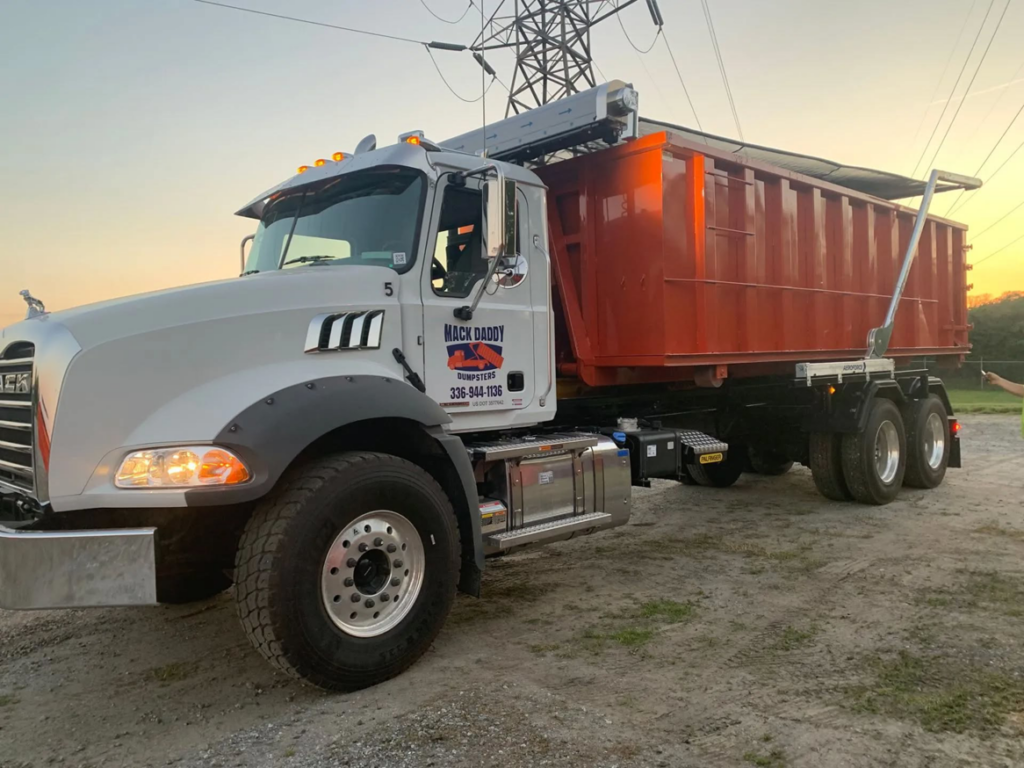 A Mack Daddy Dumpsters truck with an orange dumpster on its bed, ready for junk removal service in Winston-Salem, NC.