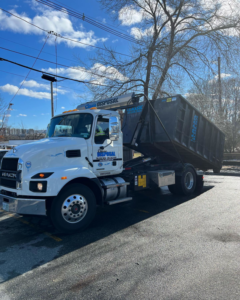 A large Classic Disposal Mack truck with a dumpster on its back, ready for junk removal services in Malden, MA.