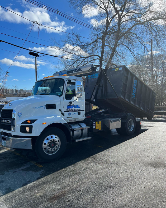 A large Classic Disposal Mack truck with a dumpster on its back, ready for junk removal services in Malden, MA.