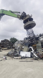A magnetic crane lifting a large load of scrap metal at Great Northwest Recycling in San Antonio, TX