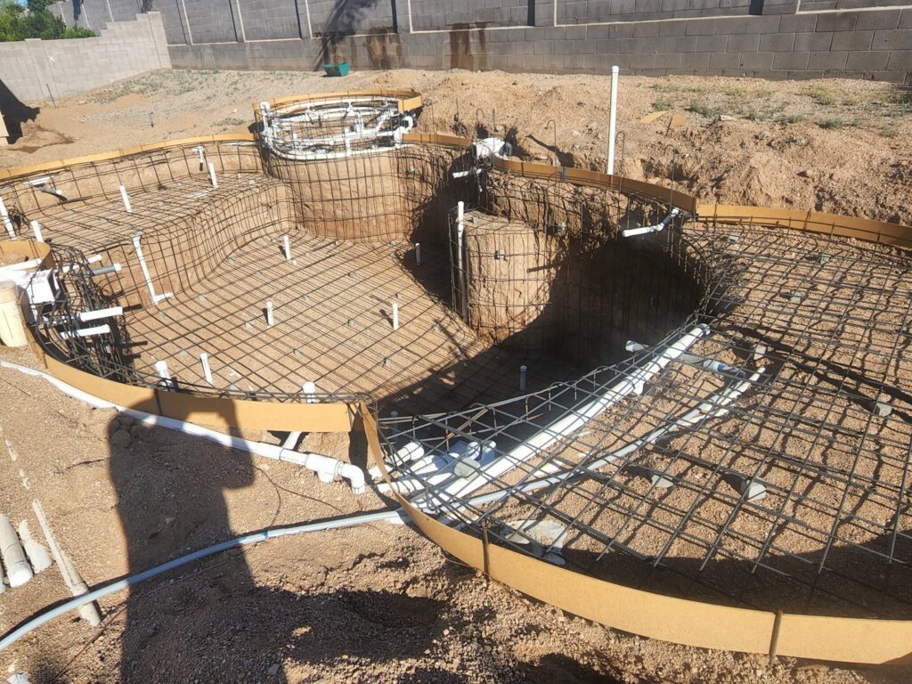 A man performing acid washing on an empty pool, a maintenance service from Aqua Squad Pools & Landscaping in Gilbert, AZ.