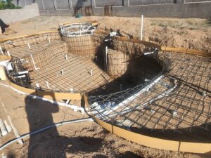 A man performing acid washing on an empty pool, a maintenance service from Aqua Squad Pools & Landscaping in Gilbert, AZ.