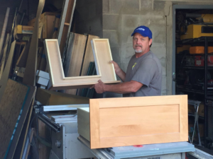 A handyman from RARE Construction, Inc. in Kansas City, MO, building custom cabinetry in a workshop.