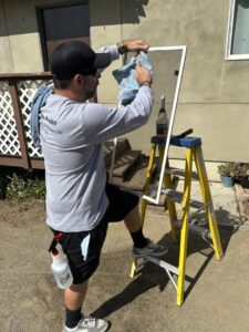 A handyman from Bring The Pane cleaning an interior window with a squeegee for a sparkling finish in Lewiston, ID.