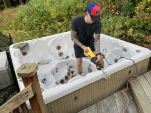 A man using a saw to cut up a hot tub on a deck for removal by Hometown Hauling 802 in Milton, VT.