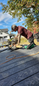 A man using a miter saw to cut wood on a new deck, demonstrating construction work by Drew's Handy Construction in Charleston, IL.