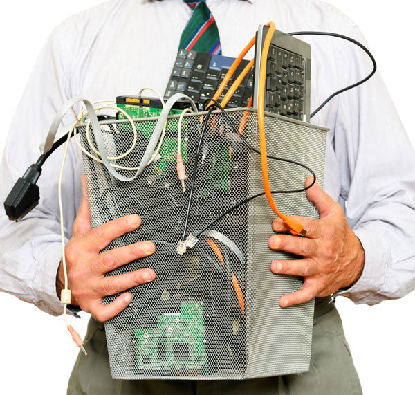 A man holding a bin filled with various electronic waste items for recycling by SES Secure E-Waste Solutions Inc. in San Diego, CA.