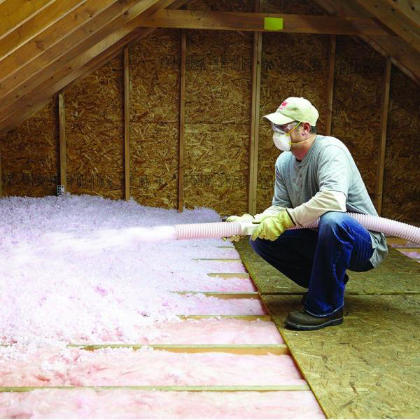 A handyman installing blown-in insulation in an attic for Alternative Weatherization in Fall River, MA.