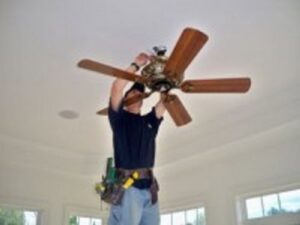 A handyman on a ladder installing a new ceiling fan, a service provided by Pocatello Handyman in Pocatello, ID
