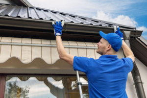 A handyman from Holaway Handyman installing new gutters on a house in Fayetteville, AR.