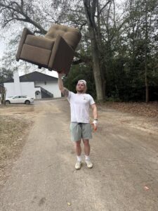A Reliable Pro team member lifting a heavy recliner chair, demonstrating junk removal services in Tallahassee, FL.