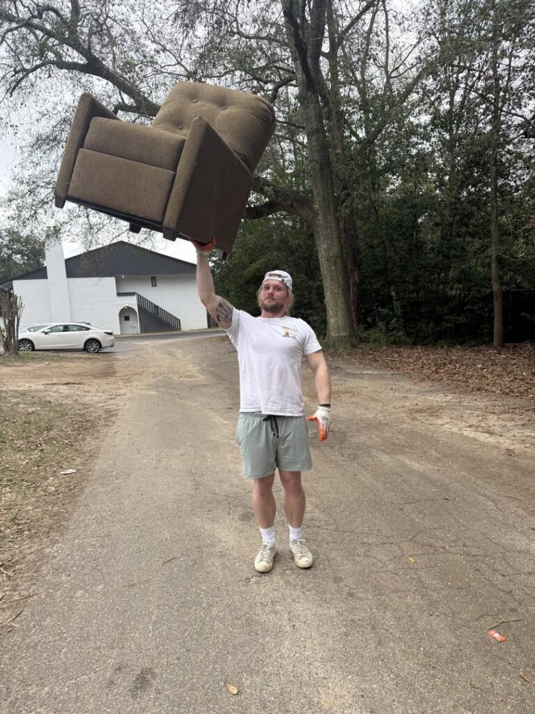 A Reliable Pro team member lifting a heavy recliner chair, demonstrating junk removal services in Tallahassee, FL.