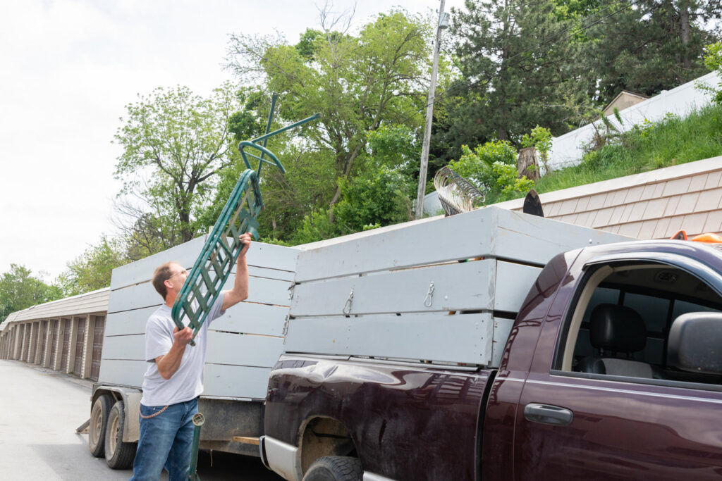 A man loading a metal frame onto a junk removal trailer for A1 Junk Removal Of Tucson, AZ.