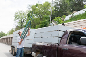 A man loading a metal frame onto a junk removal trailer for A1 Junk Removal Of Tucson, AZ.
