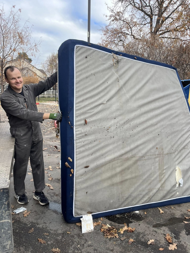 A Junk Holler employee loading an old mattress onto a truck during a junk removal job in Boise, ID.