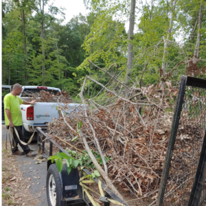 A man loading tree debris and branches onto a trailer after a job by Rustyn Page Landscaping in Harrisburg, PA.