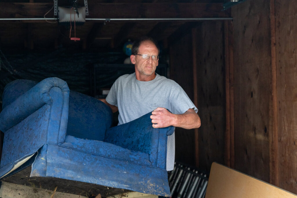 A man moving a blue armchair out of a garage for A1 Junk Removal Of Tucson, AZ.